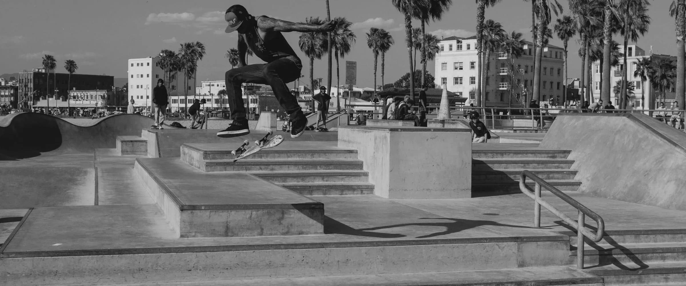 A skateboarder in mid-air above concrete steps, black and white