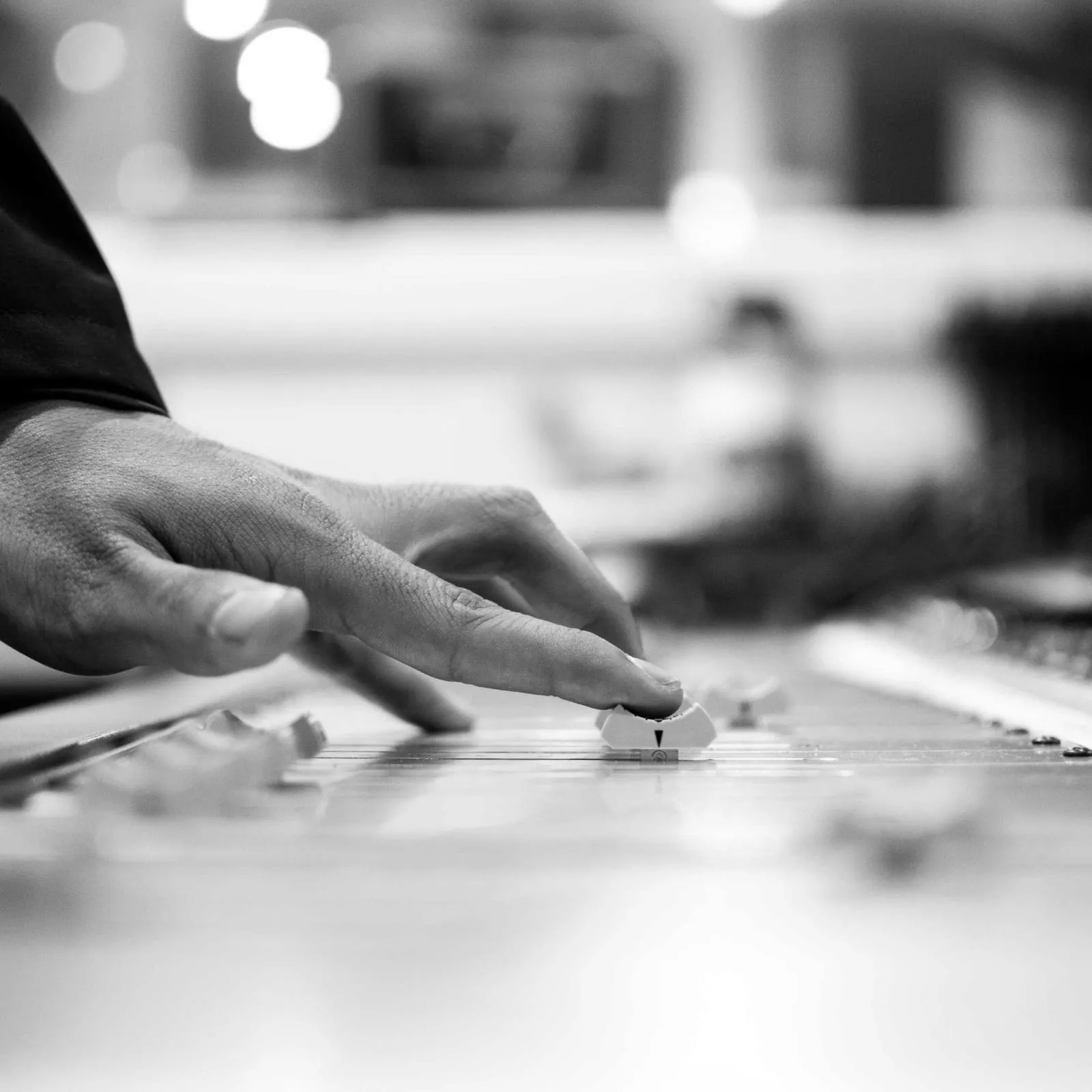 A finger moving a fader on a mixing console, black and white