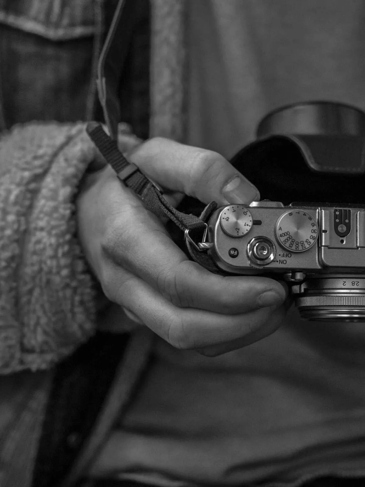Hands holding a rangefinder camera, black and white